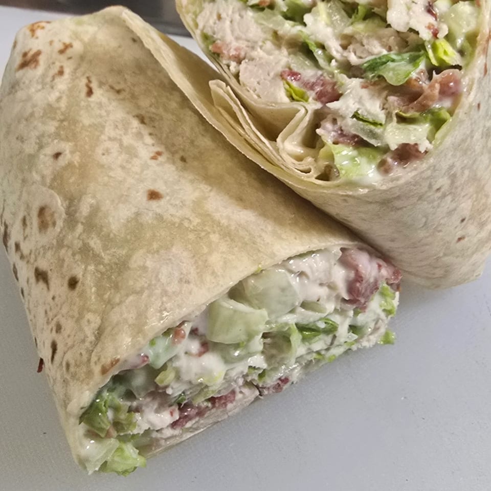 Two halves of a chicken bacon ranch wrap, filled with lettuce, chicken, and creamy dressing.